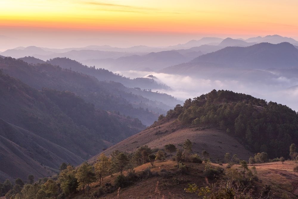 Mountain valleys in morning mist in Myanmar. Sunrise in mountains on Kalaw – Inle trek.